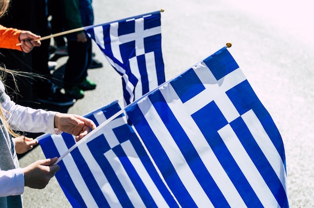 Photo midsection of woman holding greek flags while standing on road