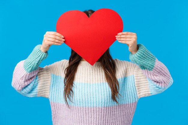 Midsection of woman holding heart shape against blue background