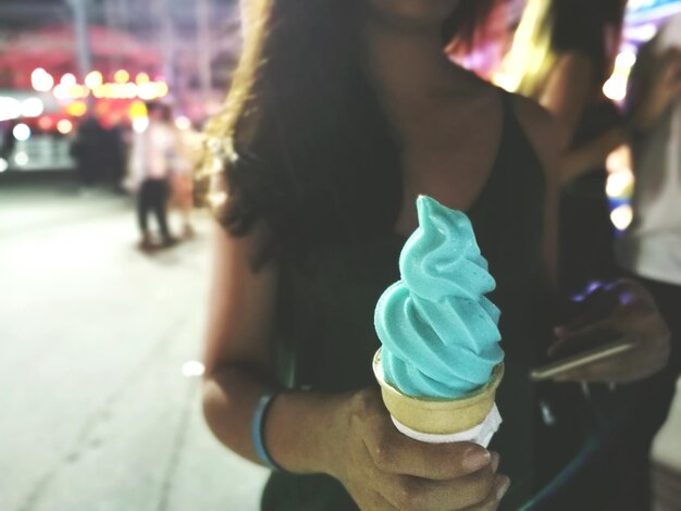 Midsection of woman holding ice cream in city