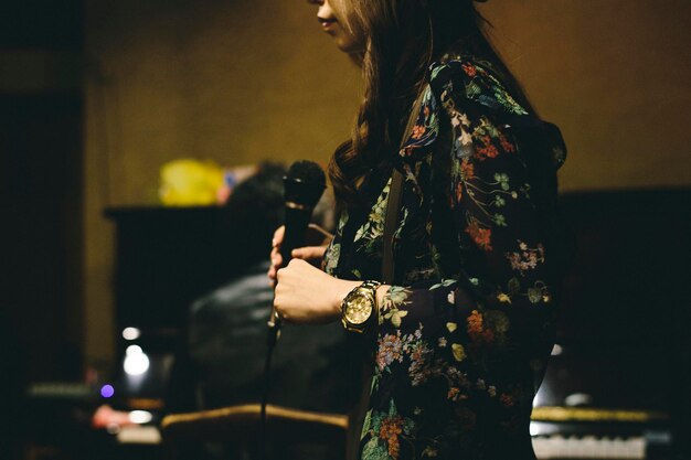 Midsection of woman holding microphone