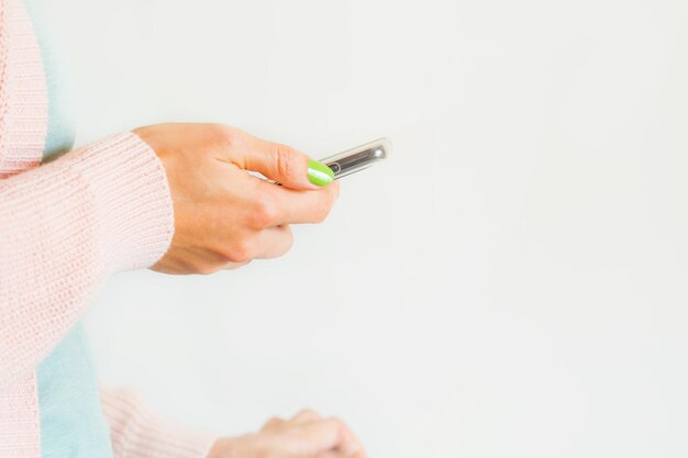 Midsection of woman holding mobile phone against white background