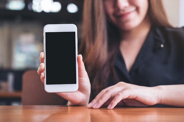 Foto sezione centrale di una donna con un telefono cellulare in un caffè