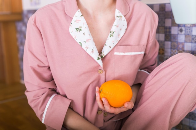 Foto sezione centrale di una donna che tiene un arancione