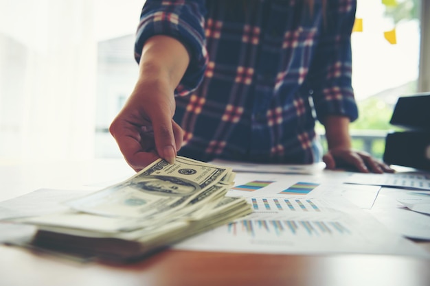 Photo midsection of woman holding paper currency on table