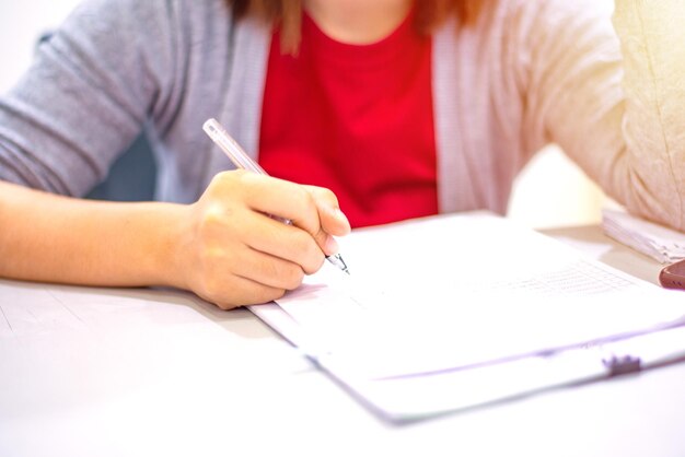 Midsection of woman holding paper while sitting on table