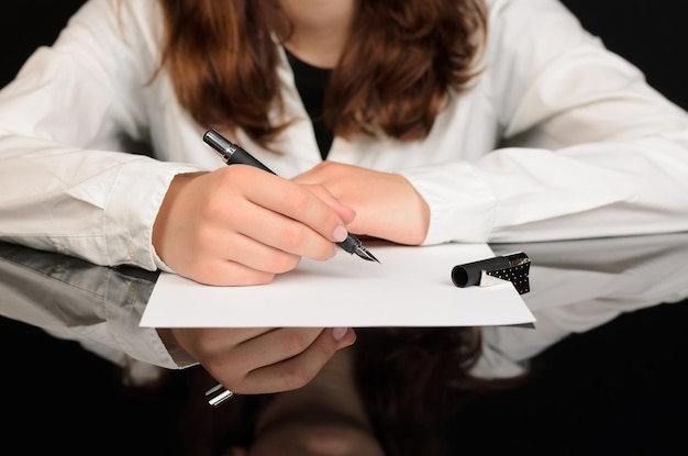 Midsection of woman holding pen over papers