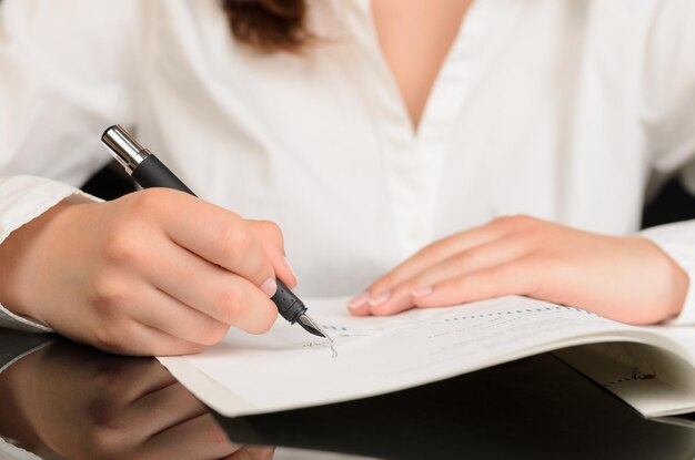 Midsection of woman holding pen over papers