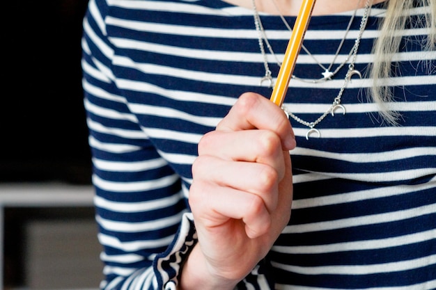 Midsection of woman holding pencil while thinking at home