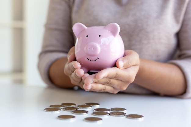 midsection of woman holding piggy bank at table