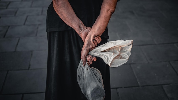 Foto sezione centrale di una donna che tiene la plastica mentre è in piedi sul marciapiede