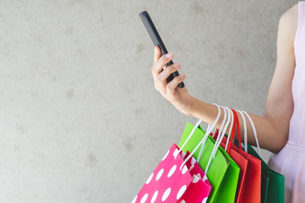 Photo midsection of woman holding shopping bags against wall