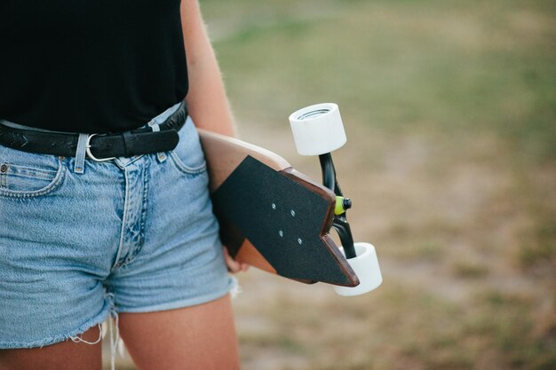 Photo midsection of woman holding skateboard while standing on field