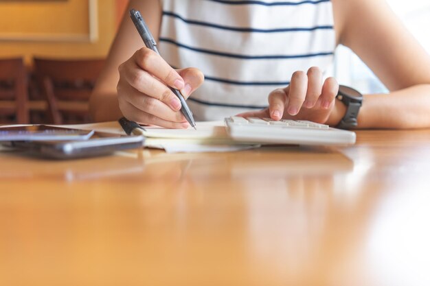 Midsection of woman holding smart phone while sitting on table