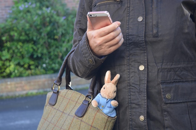 Photo midsection of woman holding smart phone while standing outdoors