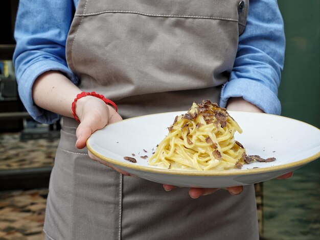 Foto sezione centrale di una donna che tiene la pasta agli spaghetti in un piatto