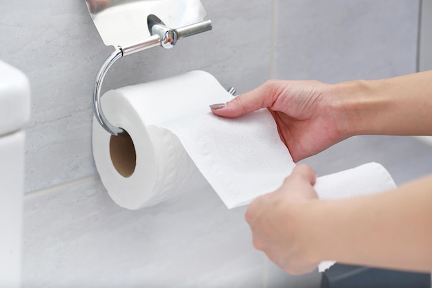 Midsection of woman holding tissue paper in bathroom
