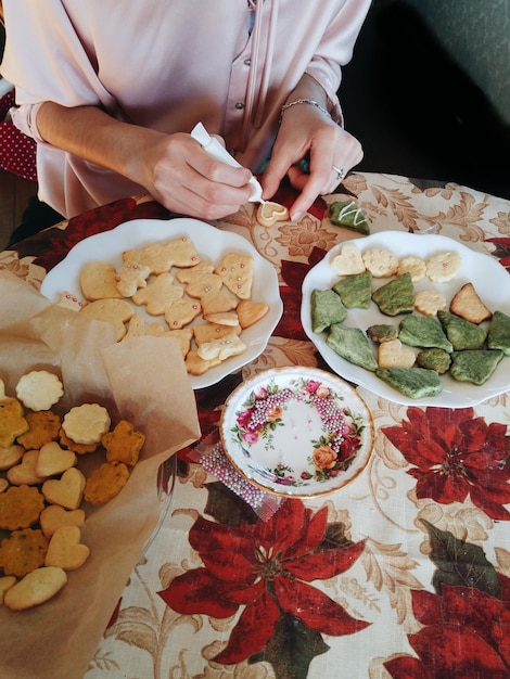 Photo midsection of woman icing cookies at home during christmas