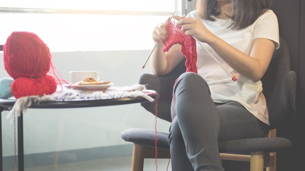 Foto sezione centrale di una donna a maglia mentre è seduta su una sedia a casa