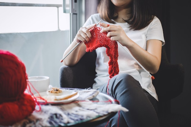 Midsection of woman knitting while sitting on table at home