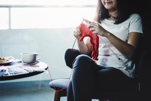 Midsection of woman knitting while sitting on table at home