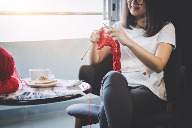 Midsection of woman knitting wool at home