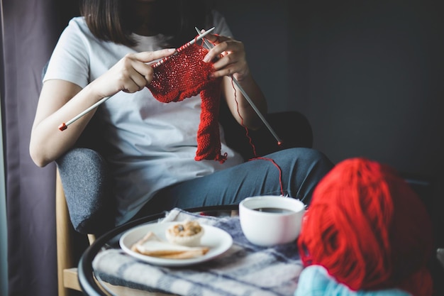 midsection of woman knitting wool while having breakfast at home
