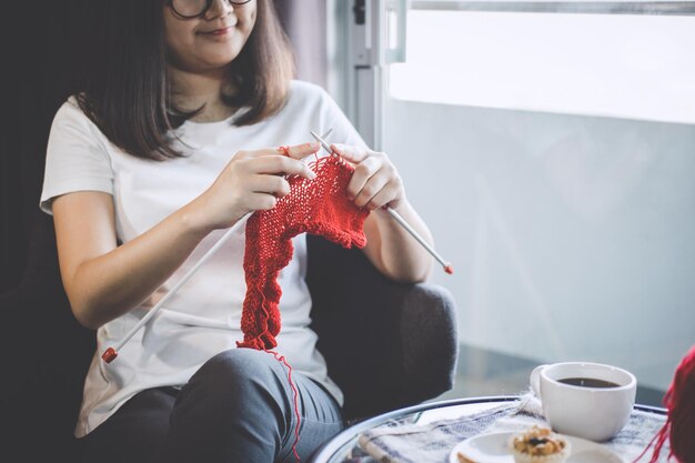 Midsection of woman knitting wool while sitting at home