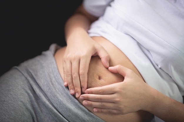 妊娠中の腹部に心臓の形を作る女性の中間部分