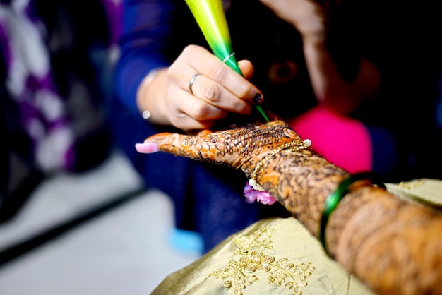 Photo midsection of woman making henna tattoo on friend palm