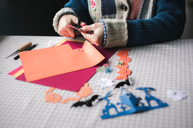 Photo midsection of woman making paper pumpkins for halloween