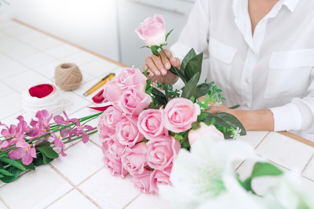 ピンクのバラの花束を作っている女性のミッドセクション