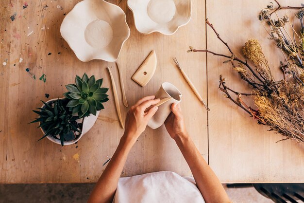 Photo midsection of woman making pottery on table in workshop