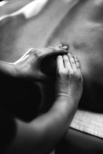 midsection of woman massaging client at spa