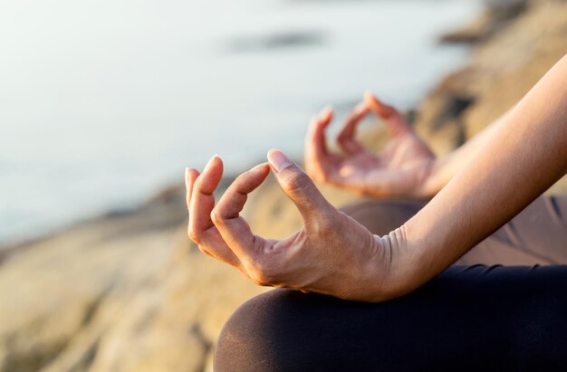 Photo midsection of woman meditating on field by sea during sunset