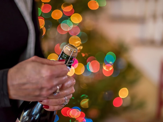 Photo midsection of woman opening champagne bottle during christmas