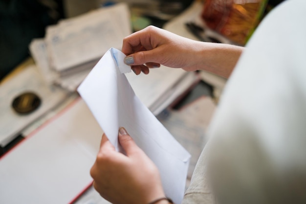 midsection of woman opening envelope