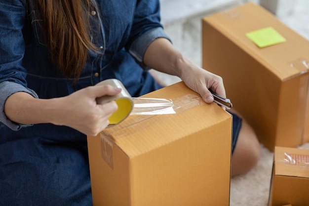 Photo midsection of woman packing boxes in office