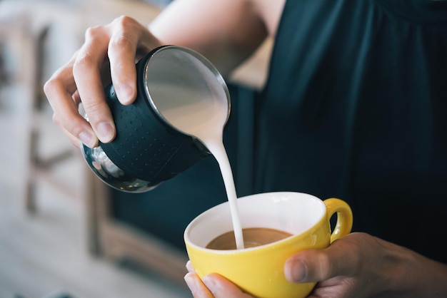 コーヒーカップにミルクを注ぐ女性のミッドセクション