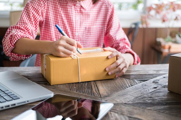 Photo midsection of woman preparing parcel on table