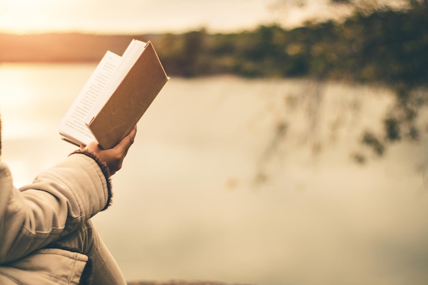 Photo midsection of woman reading book against lake