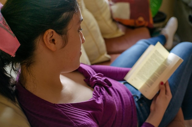 Photo midsection of woman reading book at home