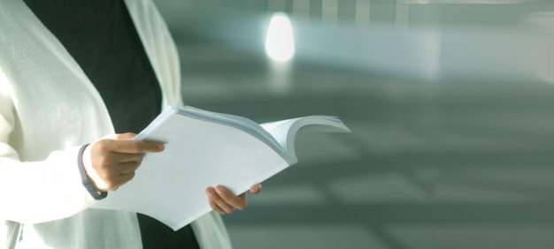 Photo midsection of woman reading book in library