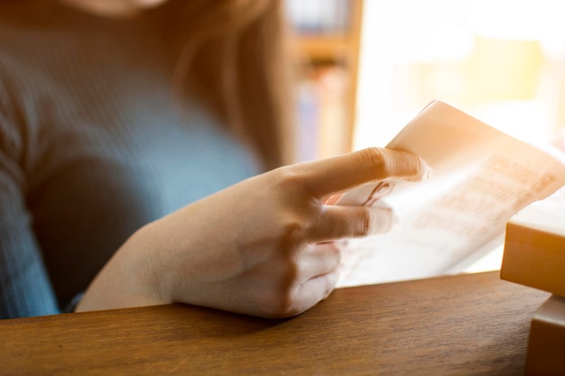 Midsection of woman reading book at table