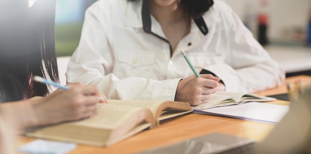 Midsection of woman reading book while sitting on table