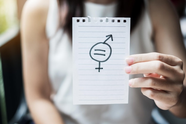 midsection of woman showing gender equality sign on paper