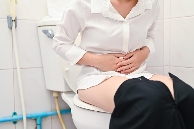 Photo midsection of woman sitting in bathroom while holding stomach at home