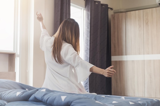 midsection of woman sitting on bed at home