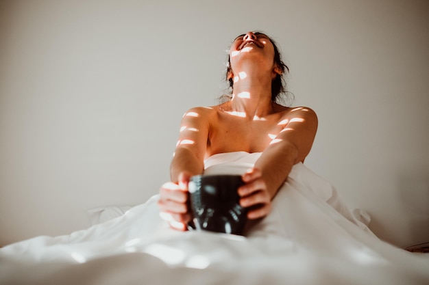 Midsection of woman sitting on bed