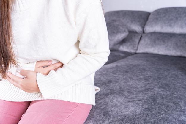 midsection of woman sitting on sofa at home