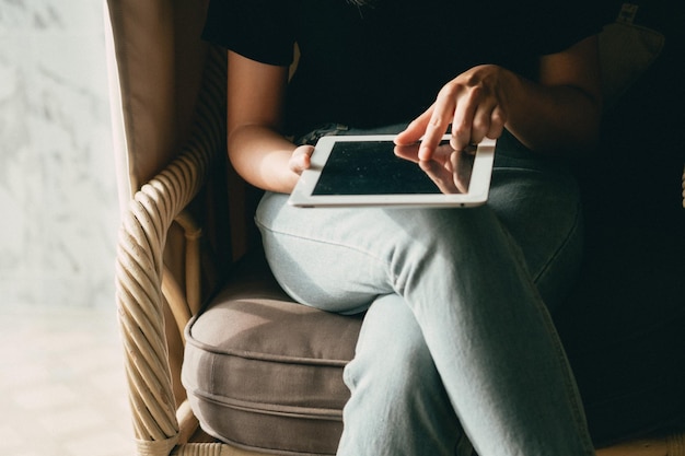 Photo midsection of woman sitting with legs crossed at knee using digital tablet at home